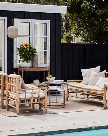 Hyggeligt indrettet terrasse med lanterner, bløde puder og grønne planter – perfekt til afslappende sommeraftener - Lene Bjerre