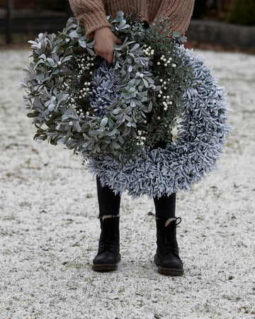 Smuk julekrans dekoreret med grønne grene, bær og rustikke detaljer, der bringer varme og hygge ind i hjemmet fra Lene Bjerre