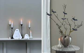 Hjemmelavet Halloween DIY: servietspøgelser lavet af stofservietter med sorte øjne omgivet af lysestager, samt grene i vase pyntet med sorte flagermus af karton.